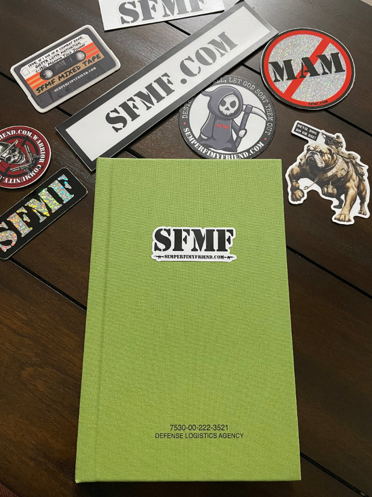 Green book with 'SFMF' logo surrounded by various stickers on a wooden surface